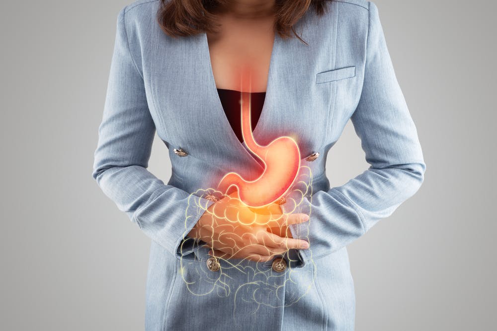 Lady clutching her stomach due to experiencing acid reflux