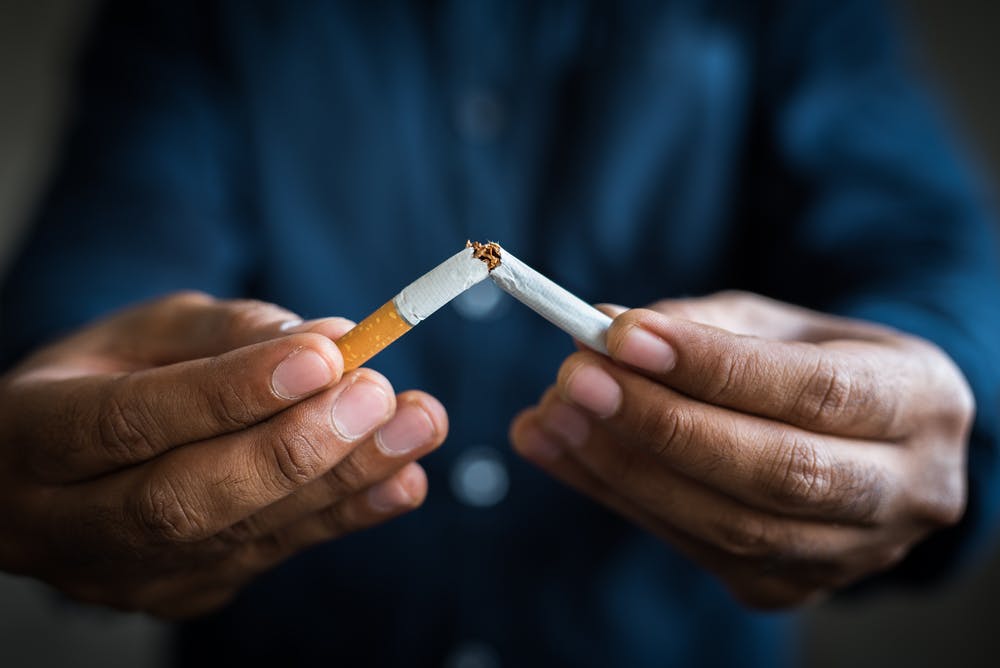Man holding a cigarette and breaking it in half to signify stopping smoking