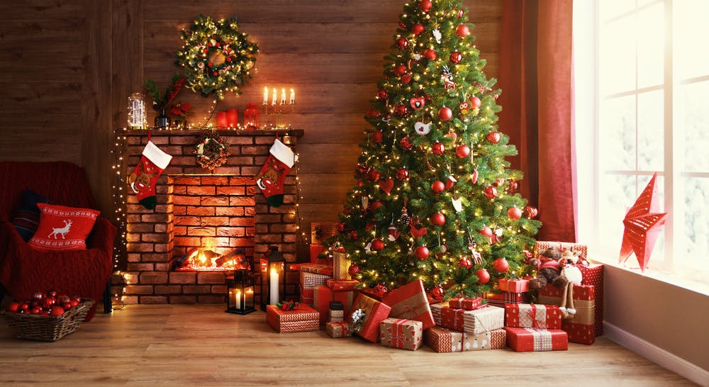 A fireplace with christmas decorations, a christmas tree and gifts