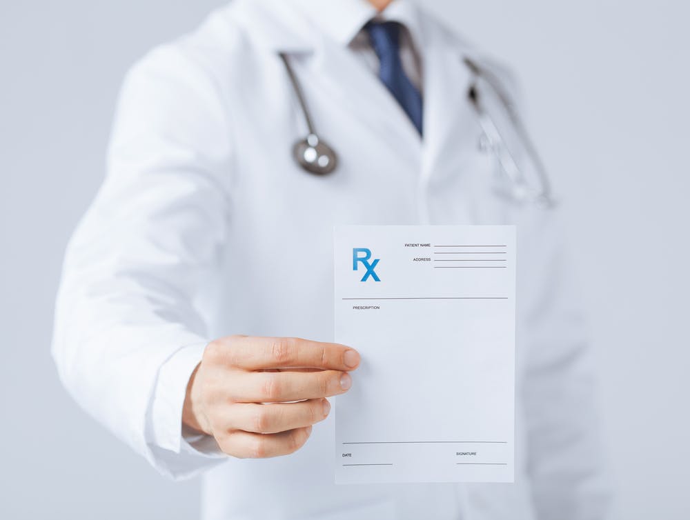A doctor holding up a medical prescription