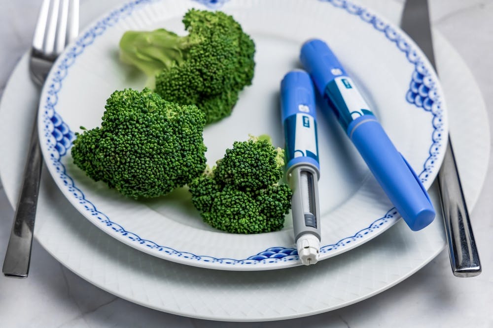 A dinner plate with brocolli and a weight loss injections
